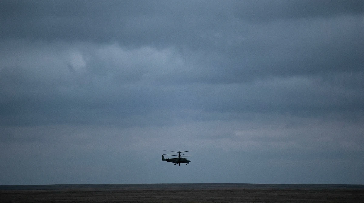 Illustration: distant silhouette of a coaxial-rotor military helicopter over open terrain