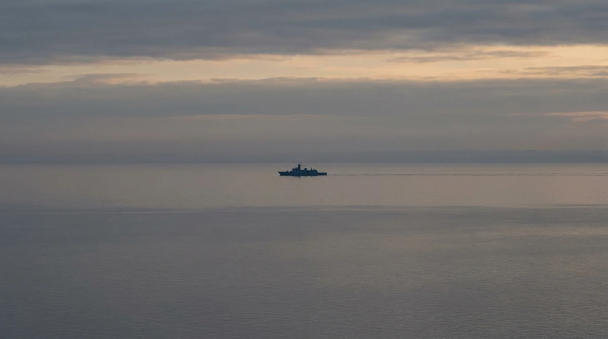 Illustration: distant warship silhouette on a calm sea at dusk