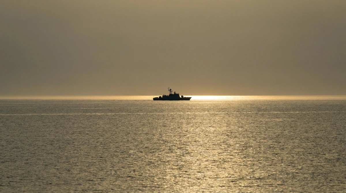 Illustration: distant silhouette of a naval patrol vessel at sea at dusk