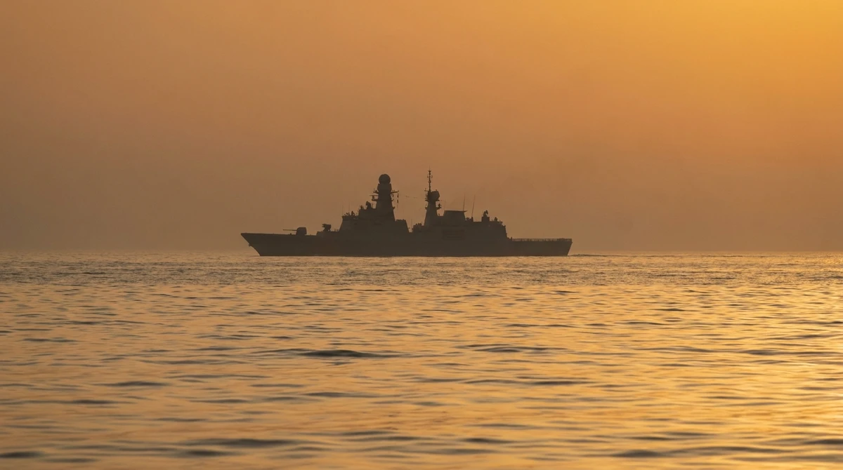 Illustration: distant silhouette of a warship at dusk in the Persian Gulf