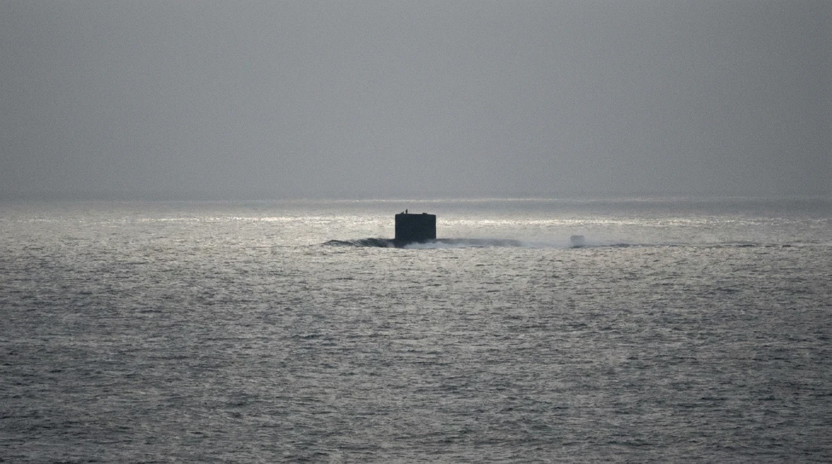 Illustration: submarine sail silhouetted at long range on the open ocean